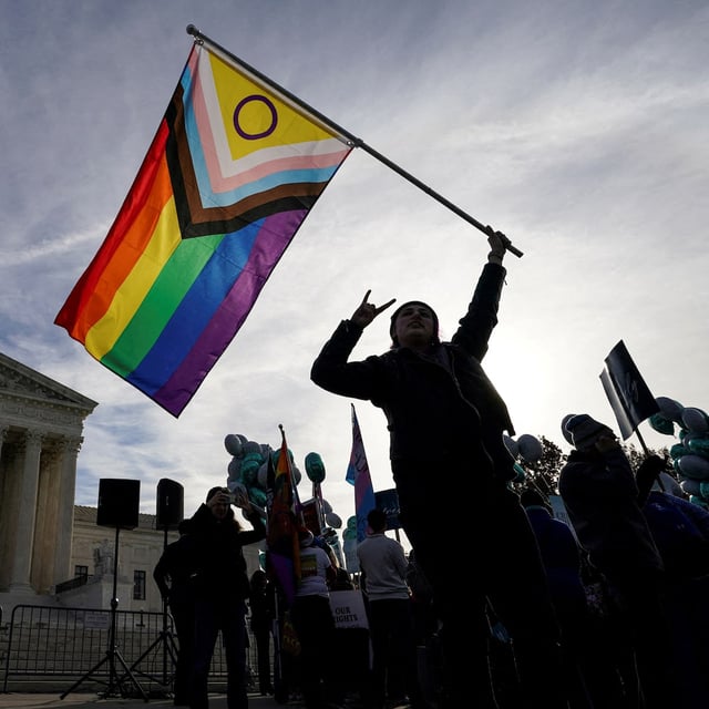 FILE PHOTO: A protester waves an LGBT rights 'pride flag' as activists gather outside the U.S. Supreme Court, where justices heard arguments in a case pitting LGBT rights against a claim that the constitutional right to free speech exempts artists from anti-discrimination laws in a dispute involving an evangelical Christian web designer who refuses to provide her services for same-sex marriages, in Washington, U.S., December 5, 2022. REUTERS/Kevin Lamarque/File Photo