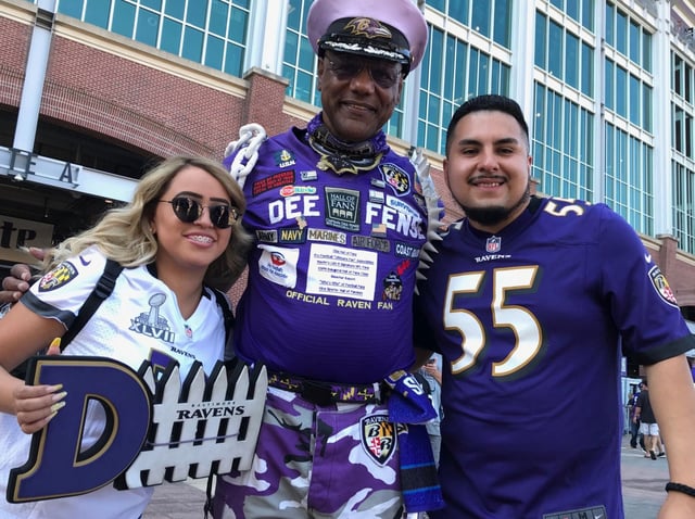 Brenda Hernandez, left, and Ezequiel Marquez, right, pose with Wes Henson, known for 24 years as Capt. Dee-Fense, at the Ravens' home opener.