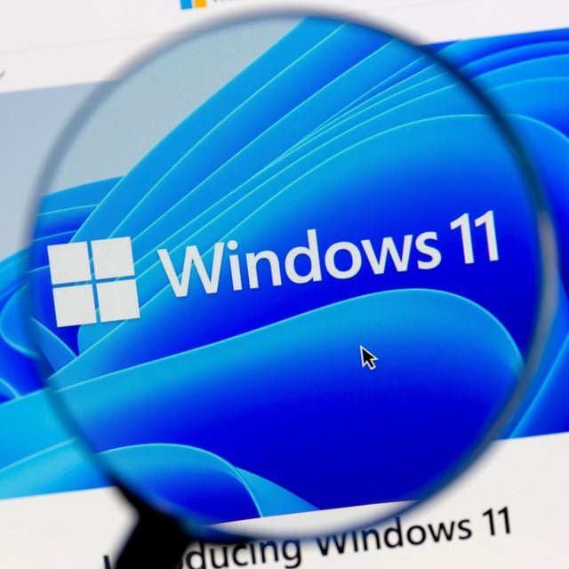The Windows 11 logo seen through a digital magnifying glass 
