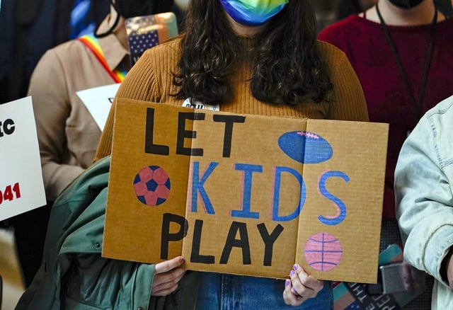 FILE - People gather to protest against a bill to ban transgender women and girls from participating in school sports that match their gender identity, during a rally at the Statehouse in Indianapolis, Wednesday, Feb. 9, 2022. (AP Photo/Michael Conroy File)