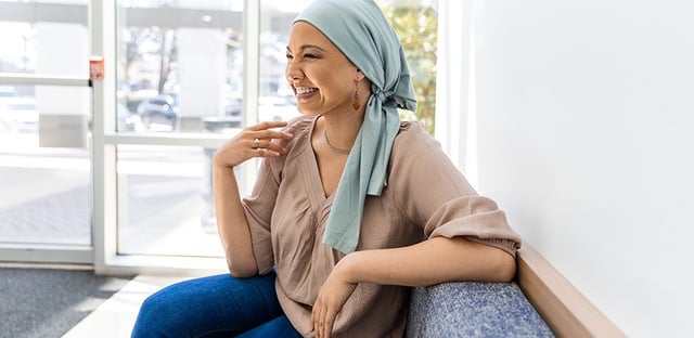 Female cancer patient in clinic lobby chats with unseen friend