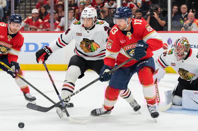 Oct 7, 2025; Sunrise, Florida, USA; Florida Panthers center Sam Reinhart (13) moves the puck against Chicago Blackhawks defenseman Wyatt Kaiser (44) during the first period at Amerant Bank Arena. (Sam Navarro-Imagn Images)