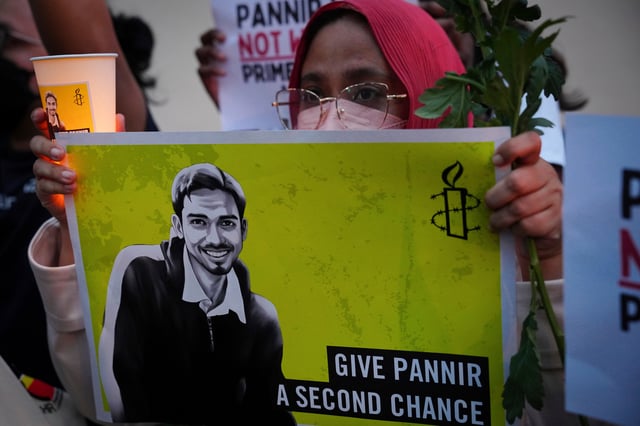 FILE -An activist holds a candle and a placard during a vigil against the impending execution of Malaysian national Pannir Selvam Pranthaman, sentenced to death for trafficking heroin into Singapore, outside the Singaporean embassy in Kuala Lumpur, Malaysia,, Feb. 19, 2025. (AP Photo/Vincent Thian, File)