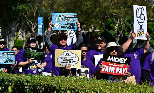 Disney employees hold up signs as they rally outside the main entrance of Disneyland Resort on July 17, 2024, ahead of a planned strike authorization vote. The strike was ultimately averted.