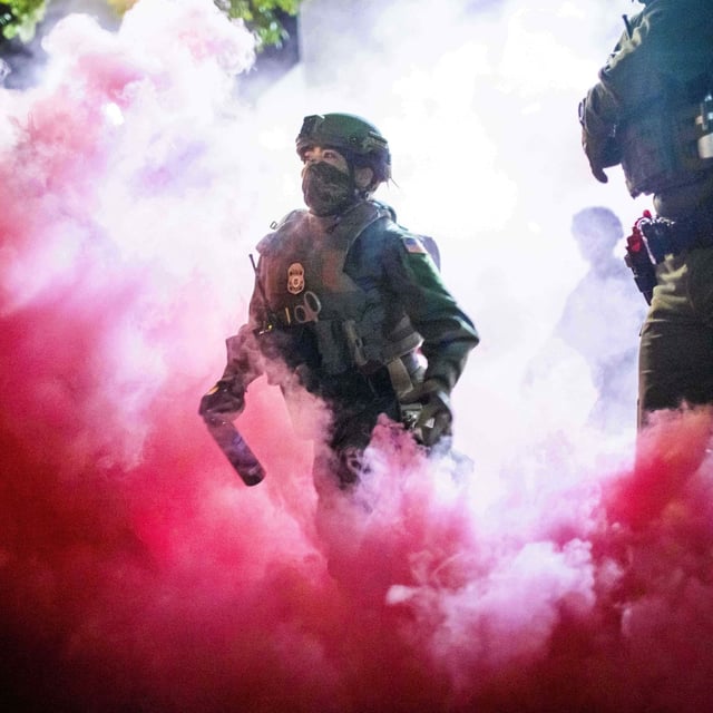 Police and federal officers throw gas canisters to disperse protesters near a U.S. Immigration and Customs Enforcement facility in Portland, Ore. on Sunday, Oct. 5, 2025. (AP Photo/Ethan Swope)