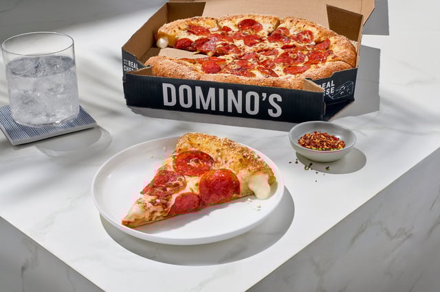 Domino's Parmesan Stuffed Crust pizza shown with the current box delivery box. The company has new logo branding and special black and gold delivery boxes coming for stuffed crust and Handmade Pan pizzas.