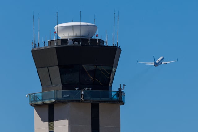 A commercial airliner takes off past the air traffic control tower at San Diego International Airport during the first day of a partial U.S. government shutdown in San Diego, California, U.S., October 1, 2025.     REUTERS/Mike Blake