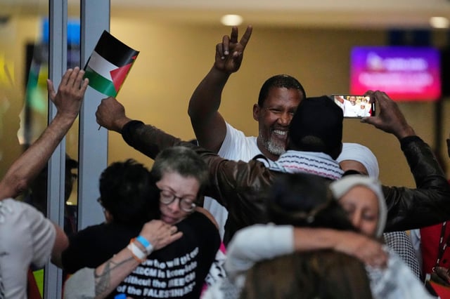 Mandla Mandela, showing victory sign and his fellow members of the Global Sumud Flotilla, at OR Tambo International Airport, in Johannesburg, South Africa, Wednesday, Oct. 8, 2025. (AP Photo/Themba Hadebe)