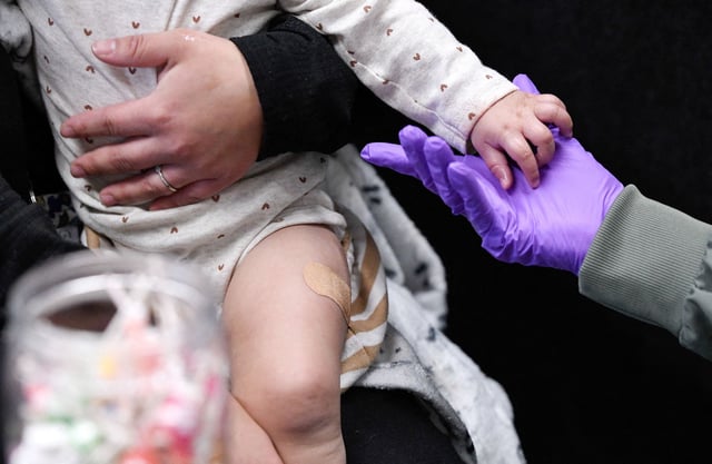Sherry Andrews, right, holds 13-month-old Jaqi Herrera’s hand after administering the first MMR vaccine dose to Herrera at the City of Lubbock Health Department in Lubbock, Texas, on February 27.