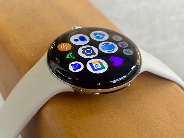 The Google Pixel Watch 4 sitting on an armrest with the app drawer icons visible on the Actua 360 display.