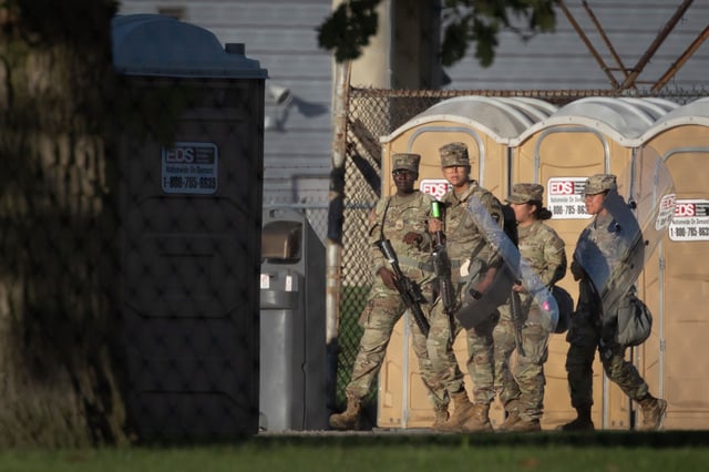 Members of the Texas National Guard carry rifles and riot shields at an army reserve training facility on October 7 in Elwood, IL.
