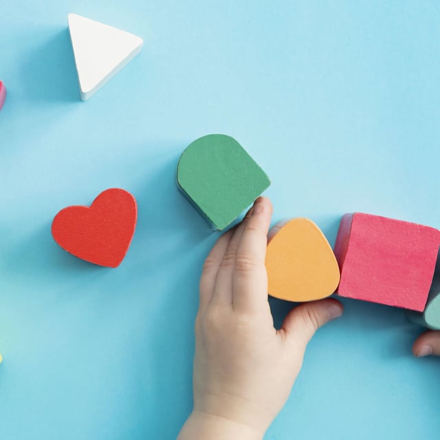 A toddler's hands play with some wooden blocks.