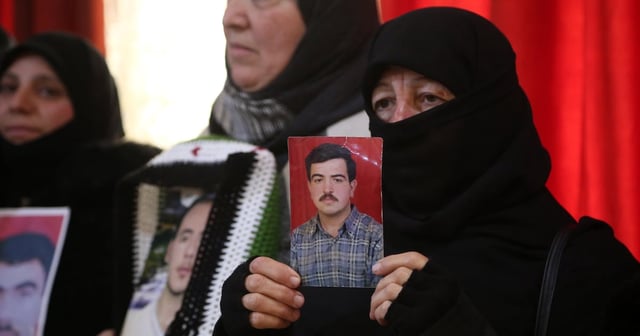 Syrian women hold pictures of missing loved ones. EPA