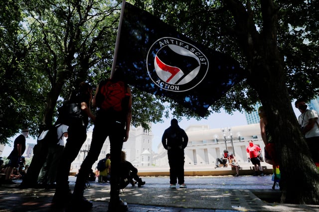 A man holds an "Antifascist Action" flag at a counter-protest organized by Solidarity Against Hate-Boston opposing a demonstration that never happened, in Boston, Massachusetts, U.S., July 11, 2020.   REUTERS/Brian Snyder