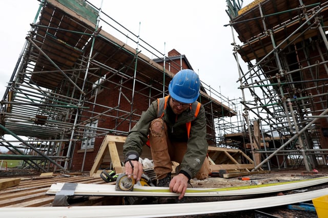 A construction worker uses a tape measure on the construction site of residential buildings in Worcester, Britain December 5, 2024. REUTERS/Temilade Adelaja