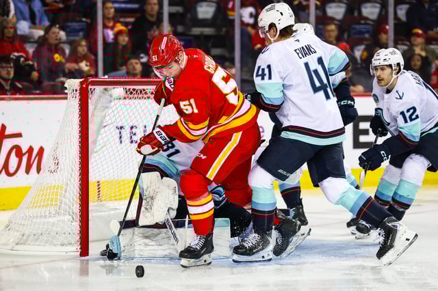 Sep 23, 2025; Calgary, Alberta, CAN; Calgary Flames right wing Matvei Gridin (51) controls the puck in front of Seattle Kraken goaltender Philipp Grubauer (31) during the second period at Scotiabank Saddledome. Mandatory Credit: Sergei Belski-Imagn Images