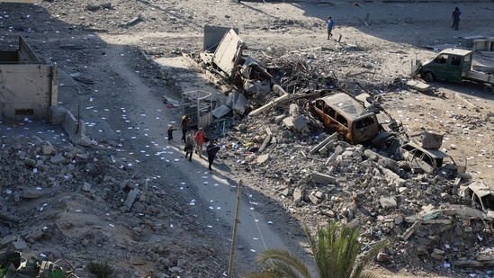 Palestinians walk near rubble following an Israeli raid, amid an Israeli military operation, in Gaza City