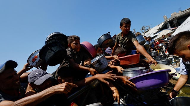 Menschen im Gazastreifen drängen sich mit Schüsseln um eine Essensausgabe.