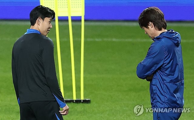 Hong Myung-bo (R), head coach of the South Korean men's national football team, chats with his captain Son Heung-min during the team's training session at Seoul World Cup Stadium in Seoul on Oct. 9, 2025. (Yonhap)