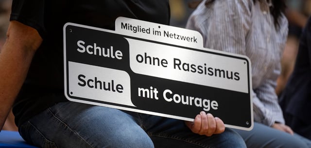 Ein Schild mit der Aufschrift „Schule ohne Rassismus – Schule mit Courage“