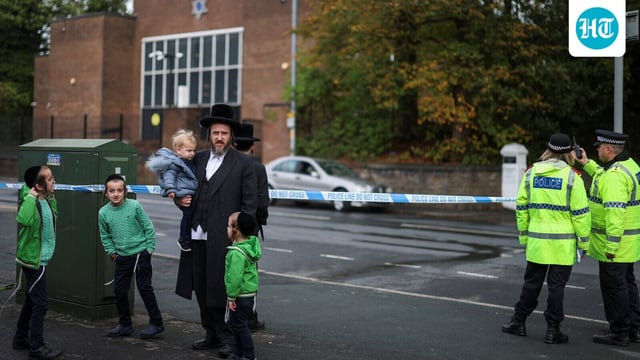 Ultra-Orthodox Jewish people stand next to police officers outside the Manchester synagogue, where multiple people were killed on Yom Kippur in what police have declared a terrorist incident, in north Manchester, Britain, October 5, 2025. REUTERS/Hannah McKay