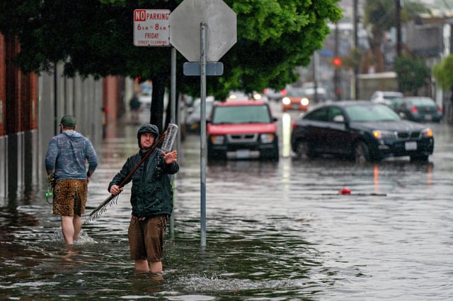 During intense storms around New Year's Eve 2022 people tried to unclog storm drains to help ease the flooding along 14th Street in the Mission District in San Francisco.
