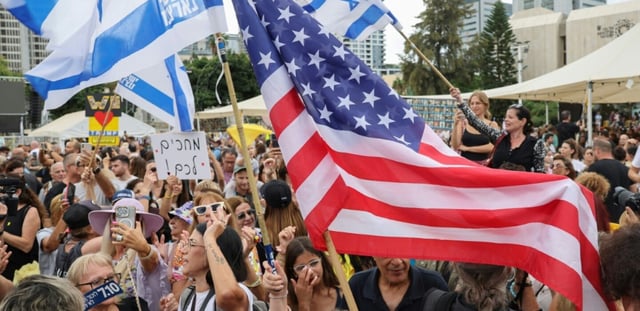 Des personnes agitent des drapeaux israéliens et américains sur la place des otages à Tel-Aviv le 9 octobre, après l'annonce d'un accord entre Israël et le Hamas