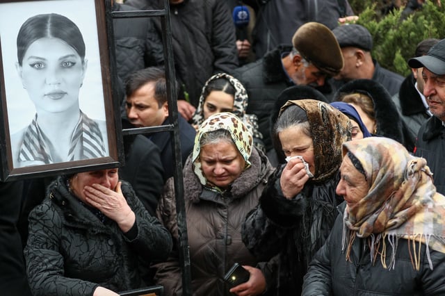 People mourn at the grave of flight attendant Hokuma Aliyeva, during the funeral of the crew members of Azerbaijan Airlines Flight J2-8243 that crashed near the Kazakh city of Aktau on December 29, 2024 in Baku, Azerbaijan.