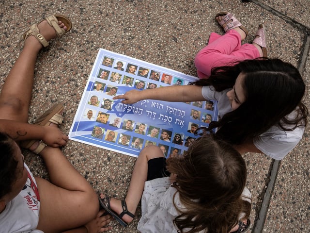 Niños miran un cartel que muestra a rehenes israelíes retenidos dentro de Gaza, en Tel Aviv. Foto:  David Guttenfelder/The New York Times