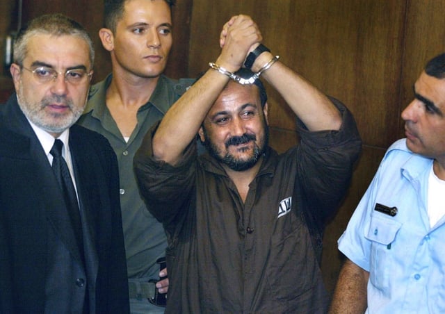 Marwan Barghouti, al centro, levanta sus manos esposadas en el aire durante el primer día de su juicio en Tel Aviv, Israel, el 14 de agosto de 2002