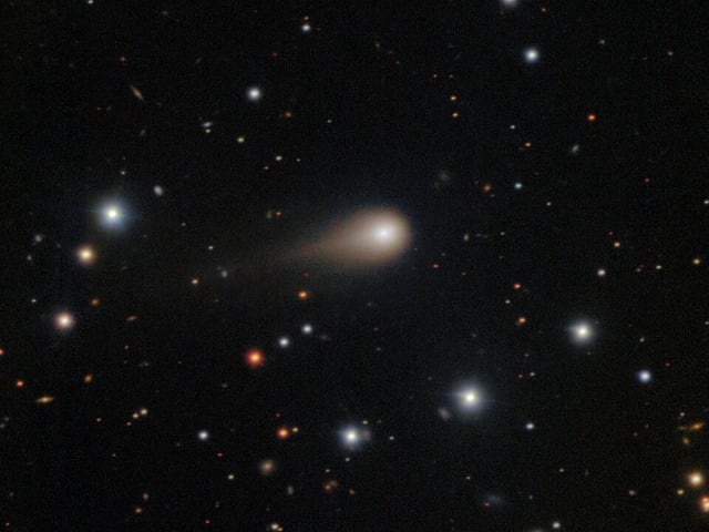 a photo of the comet 3I/ATLAS with its long tail shooting through space