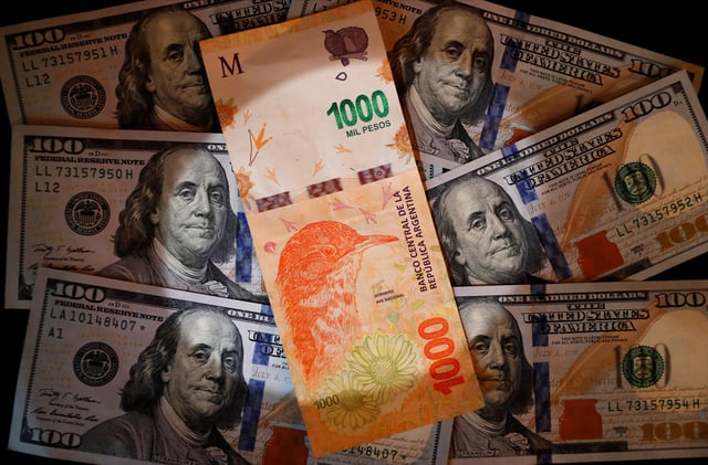 A one thousand Argentine peso bill sits on top of several one hundred U.S. dollar bills in this illustration picture taken October 17, 2022. REUTERS/Agustin Marcarian/Illustration