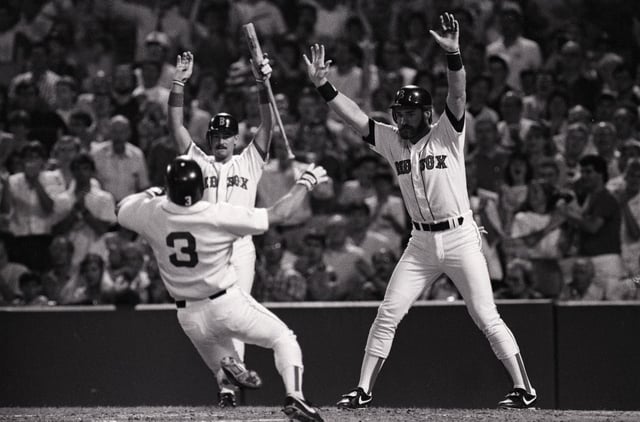 (Original Caption) 7/7/1989-Boston, MA- Red Sox players Mike Greenwell (L) and Wade Boggs (R) raise arms as teammate Jody Reed (#3) slides safely across home plate during first inning action at Fenway Park. Boggs scored ahead of Reed on a double by Nick Esasky.