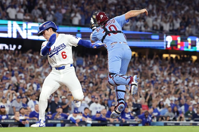 LOS ANGELES, CALIFORNIA - OCTOBER 09: Hyeseong Kim #6 of the Los Angeles Dodgers scores a run past J.T. Realmuto #10 of the Philadelphia Phillies on an error by Orion Kerkering #50 during the 11th inning in game four of the National League Division Series at Dodger Stadium on October 09, 2025 in Los Angeles, California.  (Photo by Harry How/Getty Images)