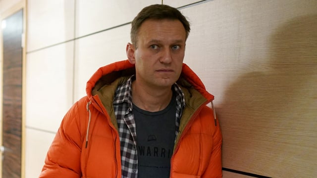 Russian opposition leader Alexei Navalny stands near law enforcement agents in a hallway of a business centre, which houses the office of his Anti-Corruption Foundation (FBK), in Moscow on December 26, 2019.