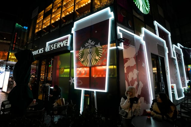 People enjoy coffee outside a Starbucks cafe at an outdoor shopping mall in Beijing on Saturday, Dec. 23, 2023. It was tumultuous 2023 for the Chinese economy. Some of the world’s biggest brands said they were weighing, or already have decided, to shift manufacturing away from China amid unease about security controls, government protection of their Chinese rivals and Beijing’s wobbly relations with Washington. But there was at least one bright spot for Beijing amid all the tough news about declining foreign investment: American fast food companies have announced a surge of investment in a market of 1.4 billion people. KFC, McDonald’s and Starbucks are among companies in recent months that have announced plans for major investment in China. (AP Photo/Andy Wong)
