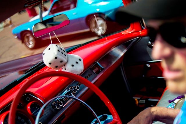 Fuzzy dice hangs from a car's rear-view mirror.