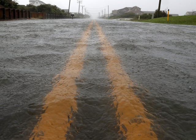 A flooded street is seen in close-up, with double yellow lines under several inches of water.