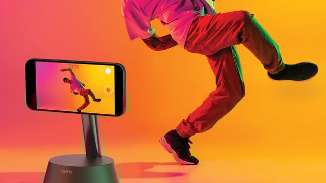 A person posing in front of an iPhone attached to Belkin's Auto-Tracking Stand Pro.