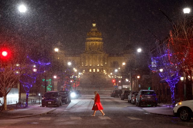 A woman crosses the street in front of the Iowa State Capitol Building on Jan. 8, 2024 in Des Moines.