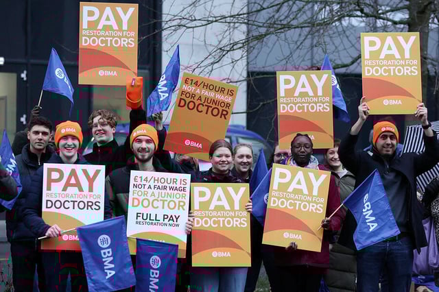 Junior doctors hold signs on a picket line outside the Royal University Hospital during a national strike over pay and conditions, in Liverpool, England, Jan. 3, 2024. 