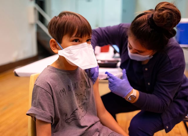 Ephrem Chen, 9, receives his COVID-19 booster shot and a flu vaccine from an IDPH nurse during a walk-in clinic on Dec. 3, 2023, at St. Procopius School in the Pilsen neighborhood of Chicago. (Brian Cassella/Chicago Tribune/Tribune News Service via Getty Images)