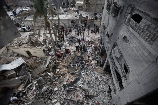 Palestinians look at the destruction after an Israeli strike in Kahan Younis, Gaza Strip, Friday, Jan. 12, 2024. AP Photo/Mohammed Dahman)