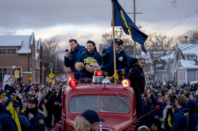ANN ARBOR, MICHIGAN - JANUARY 13: Trevor Keegan #77, Blake Corum #2 of the Michigan Wolverines and head coach Jim Harbaugh of the Michigan Wolverines cheer during the Michigan Wolverines football National Championship parade on January 13, 2024 in Ann Arbor, Michigan. (Photo by Nic Antaya/Getty Images)