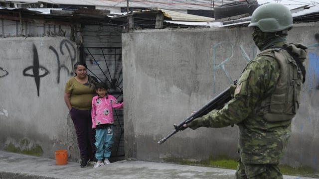 A soldier walks past residents on the south side of Quito, Ecuador, in the wake of the apparent escape of a powerful gang leader from prison, Jan. 12, 2024 (AP Photo/Dolores Ochoa).