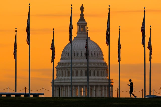 FILE – An early morning pedestrian is silhouetted against sunrise as he walks through the American flags on the National Mall with the U..S Capitol Building in the background in Washington Nov. 7, 2022. (AP Photo/J. David Ake, File)