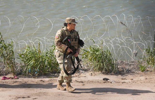 An Army National Guard soldier patrols the banks of the Rio Grande in Eagle Pass on Monday. The federal government has accused the state of using the Guard to block Border Patrol agents from conducting "operationally necessary" activities.