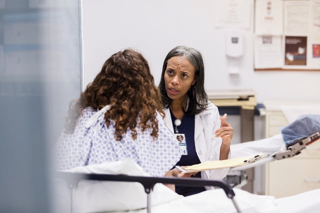 A teenage girl speaks with a doctor in a hospital emergency room