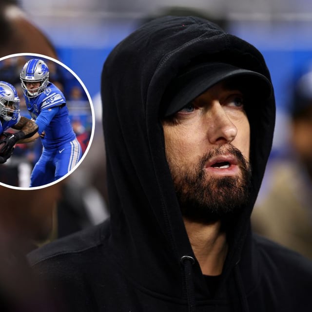 Eminem stands on the field prior to an NFL wild-card playoff football game between the Detroit Lions and the Los Angeles Rams at Ford Field on January 14, 2024 in Detroit, Michigan, and Jared Goff #16 of the Detroit Lions hands the ball off to David Montgomery #5 during the game. Eminem has asked that the Lions coach lets him play on the team in an upcoming game.
