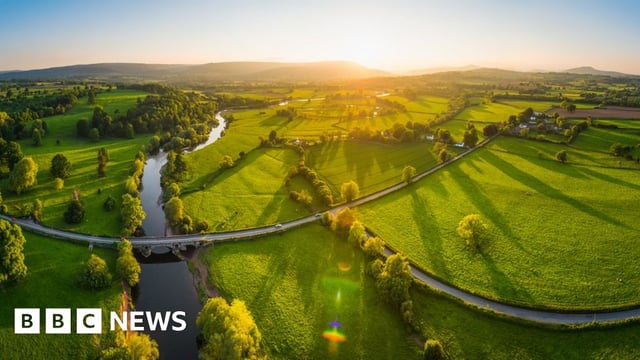 Sunset illuminating green pasture, agricultural crops, farms, villages and the distant mountains beyond the River Usk
